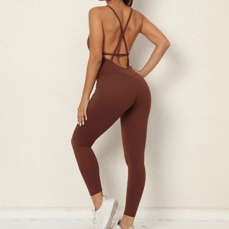 Woman in brown seamless yoga jumpsuit, open back design, wearing white sneakers, showcasing style and comfort for workouts.